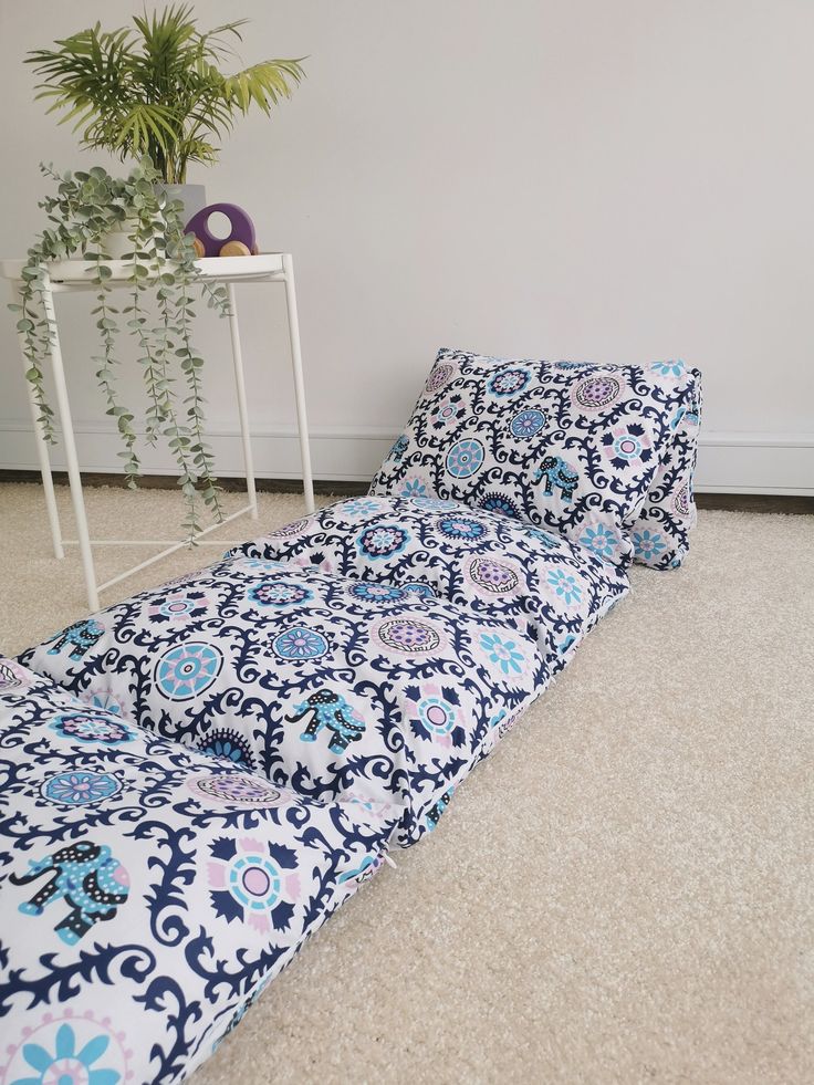 a blue and white bed sitting on top of a floor next to a potted plant