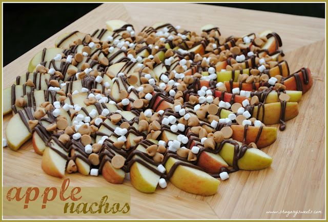 apples and marshmallows are arranged on a cutting board with chocolate drizzle