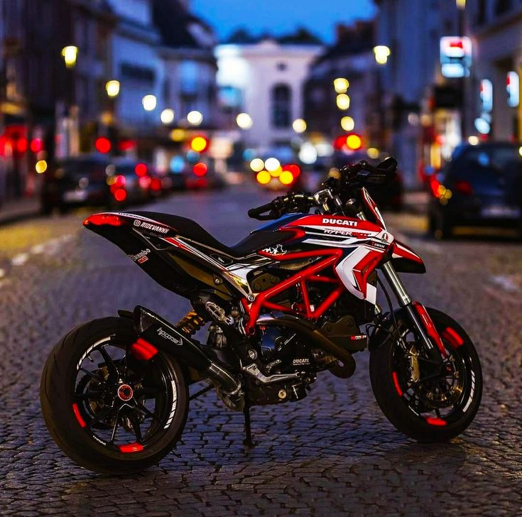 a red and black motorcycle parked on the side of a street