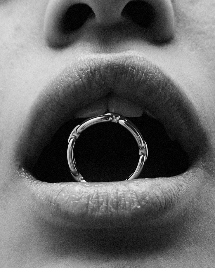 a woman's mouth with a ring on the top of her lip in black and white