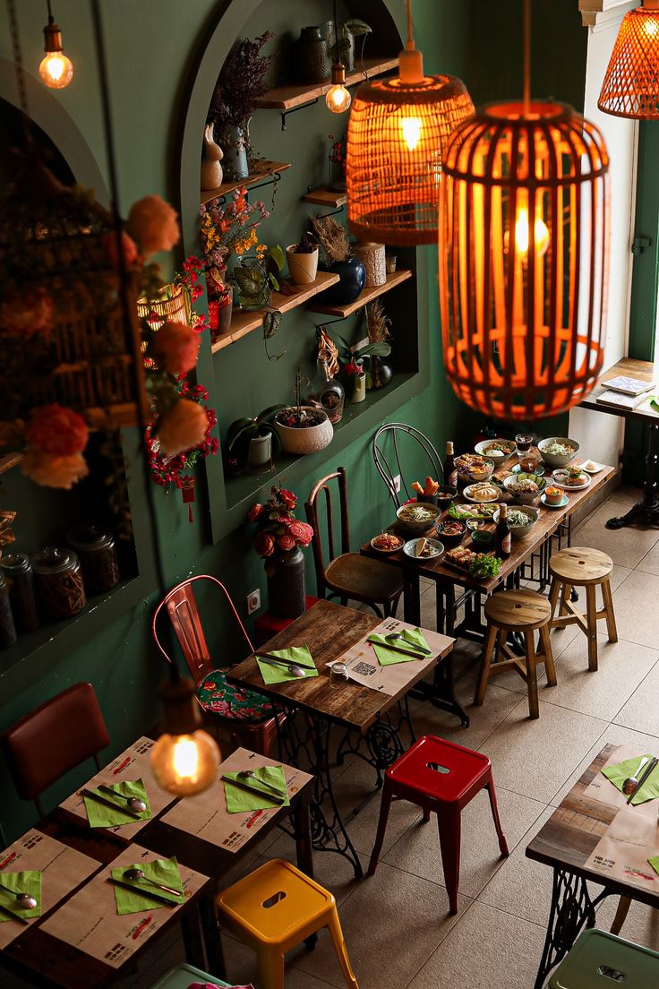 an empty restaurant with tables and chairs in the center, lit up by lamps hanging from the ceiling