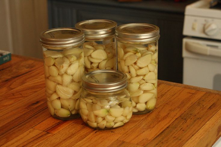 four jars filled with white beans sitting on top of a wooden counter next to an oven