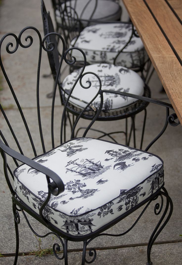 the chairs are lined up on the side walk near the table and bench outside in the day time