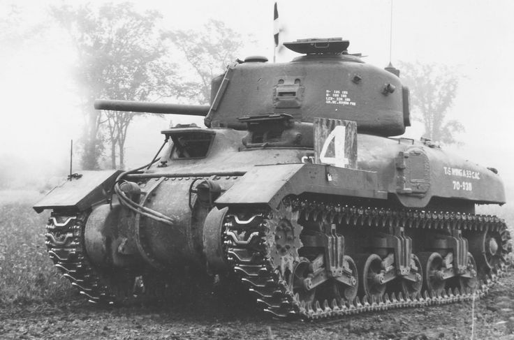 an old tank sitting in the middle of a field with trees and fog behind it