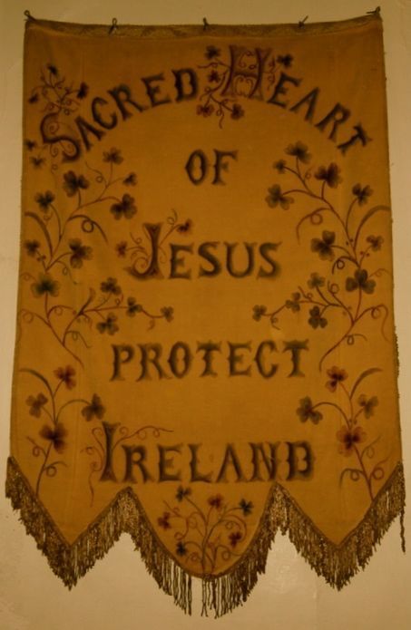 an old banner hanging on the wall that says, sacred heart of jesus protect ireland