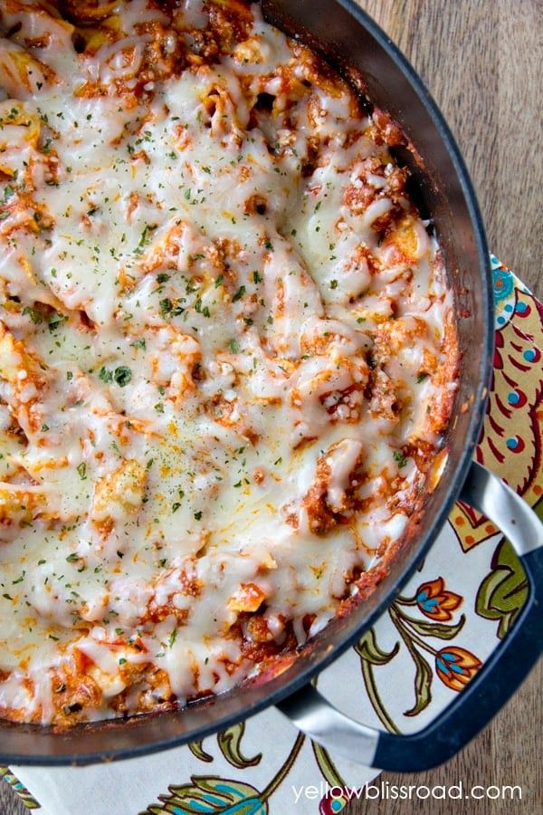 a casserole dish with cheese and meat in it on a floral patterned plate