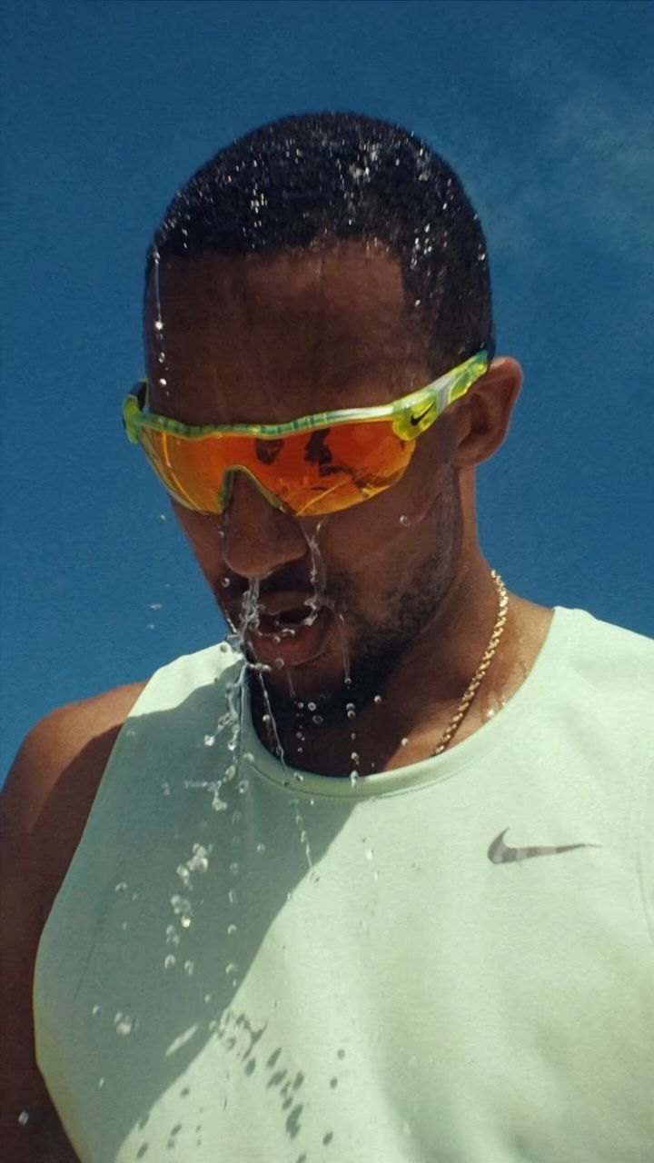 a man wearing sunglasses and drinking water from a fountain with his face covered in sun glasses