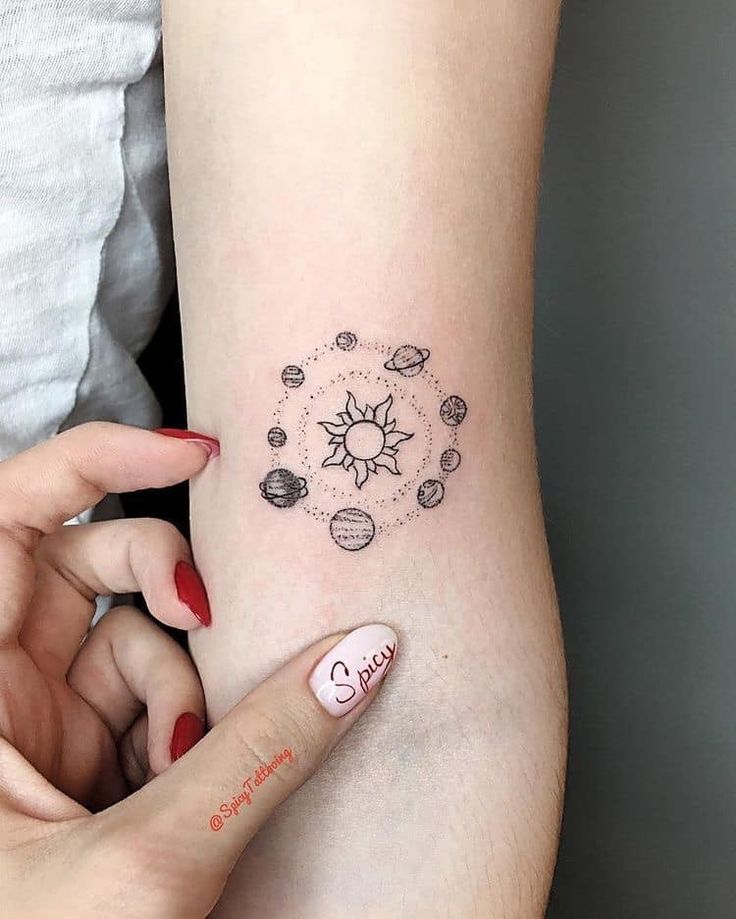 a woman's arm with a small sun and planets tattoo on her left side