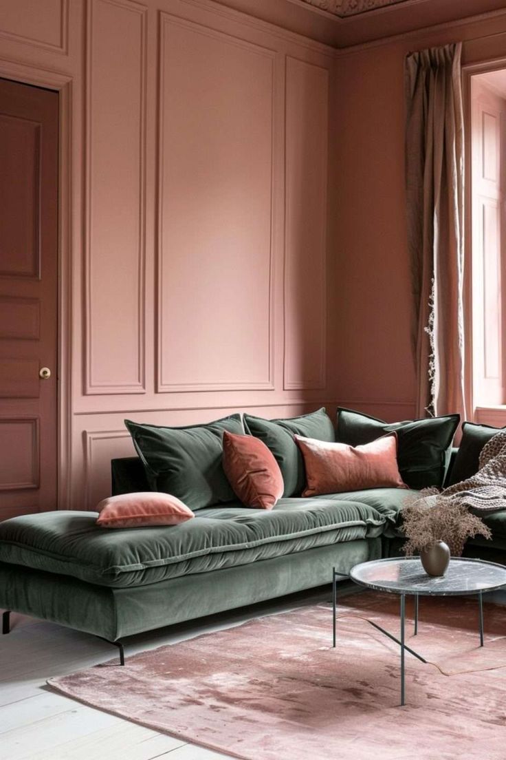 a living room with pink walls and green couches in front of a large window