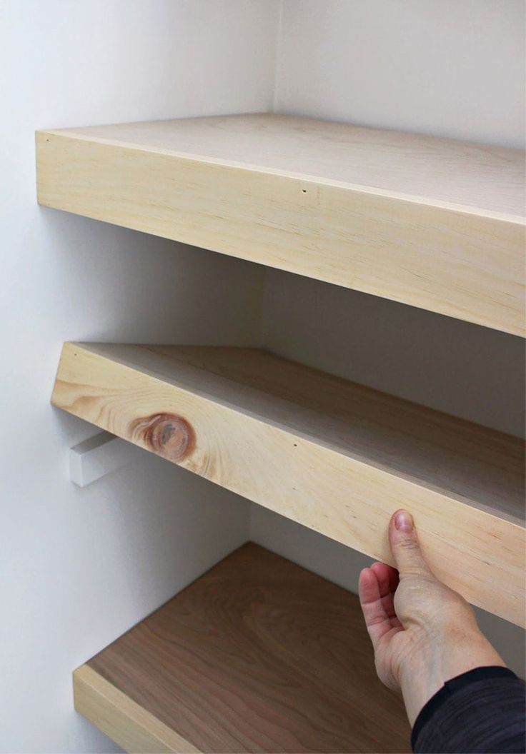 a person is reaching for the bottom shelf of a bookshelf with no shelves