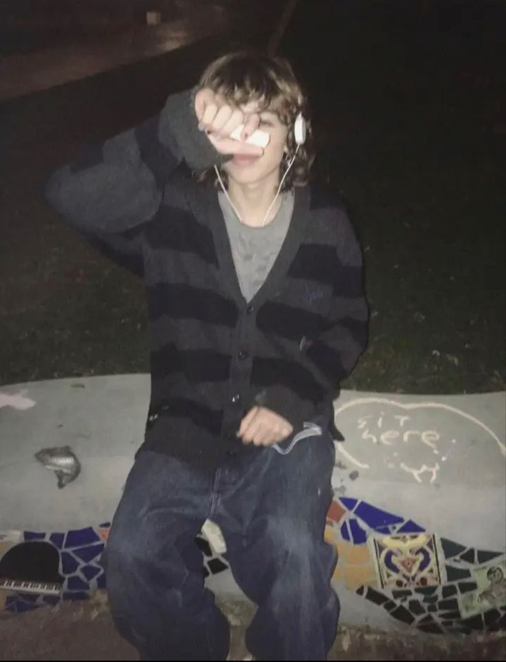 a young man sitting on top of a cement slab