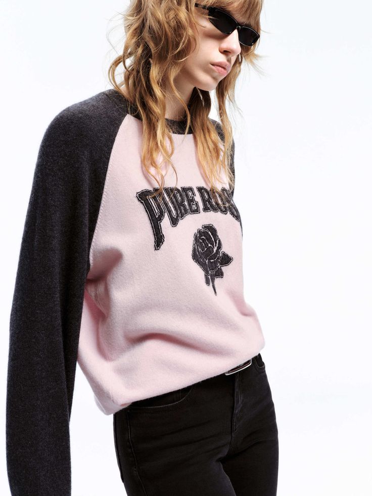 a woman in black jeans and a pink sweater