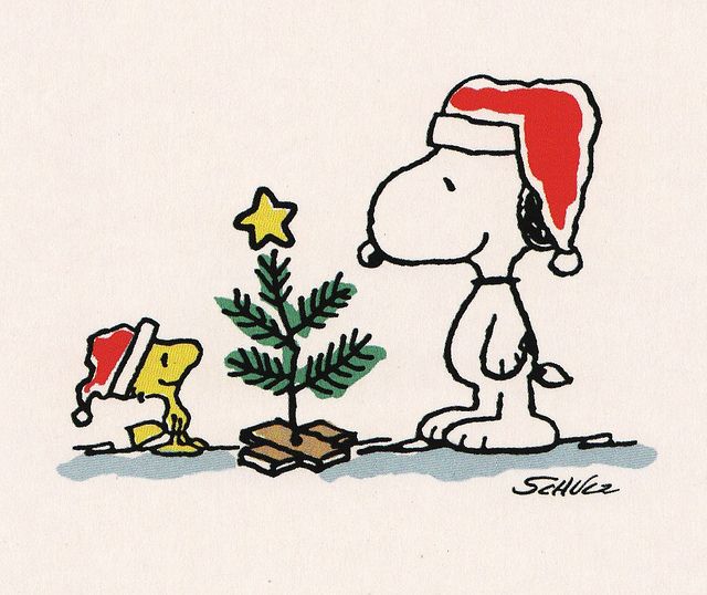 a charlie brown christmas card with a dog and a tree on the ground next to it