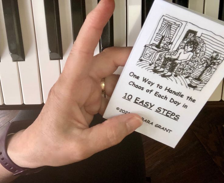 a person holding up a card with an image of a man playing the piano on it