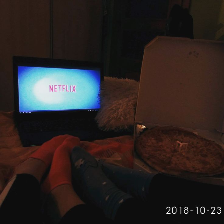 a laptop computer sitting on top of a bed in front of a pizza box with the word netflix written on it