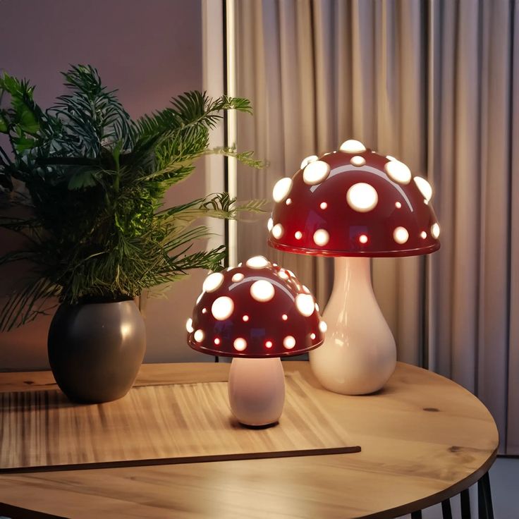 two mushroom shaped lights sitting on top of a table next to a potted plant