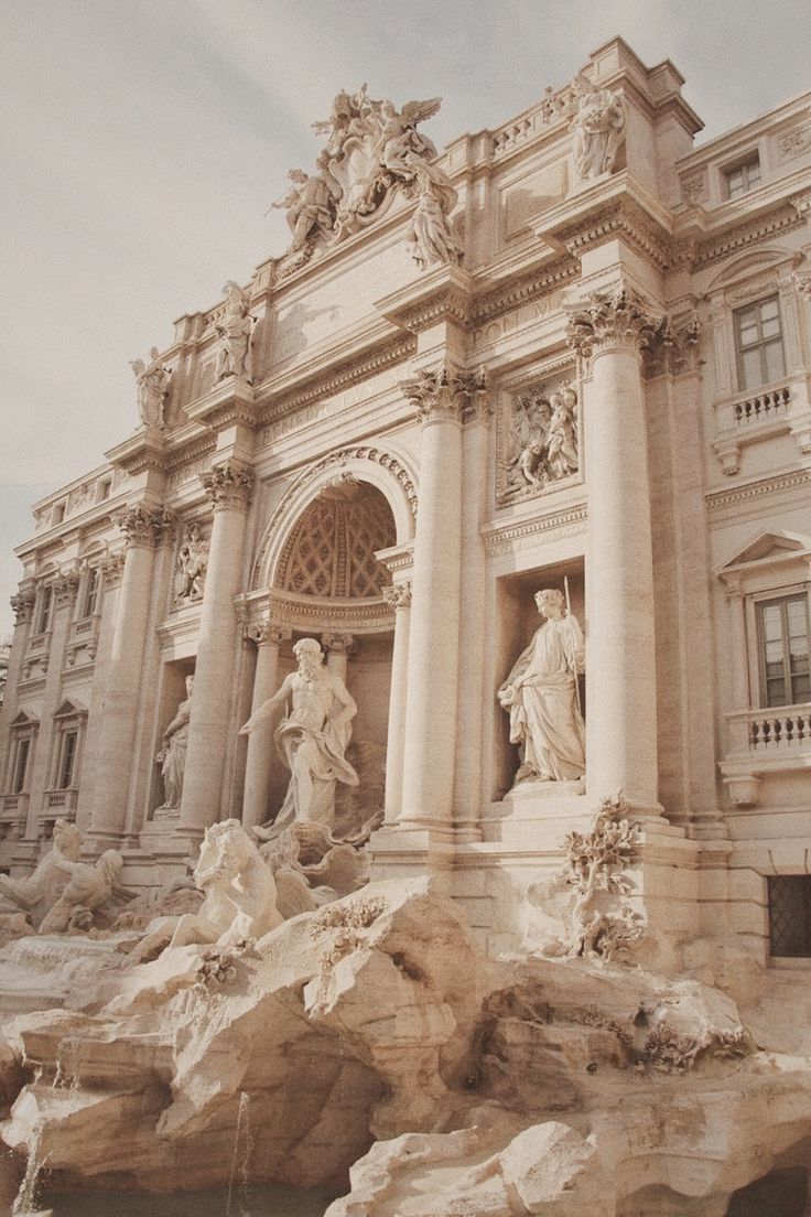 an ornate building with statues and fountains in front