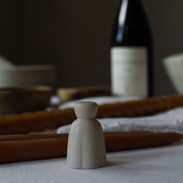 a white figurine sitting on top of a table next to bottles of wine