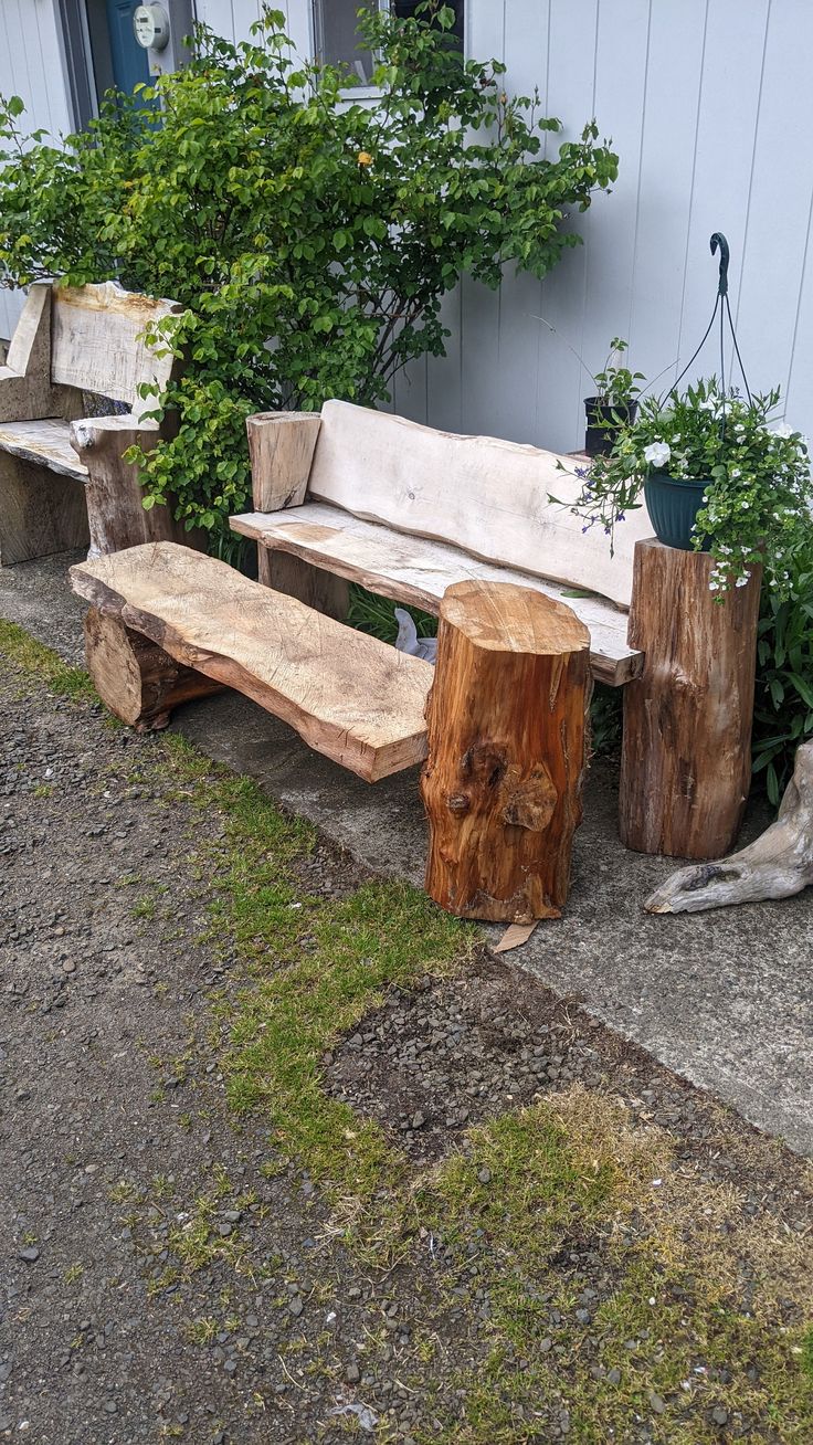 two wooden benches sitting next to each other on the side of a building with plants growing out of them