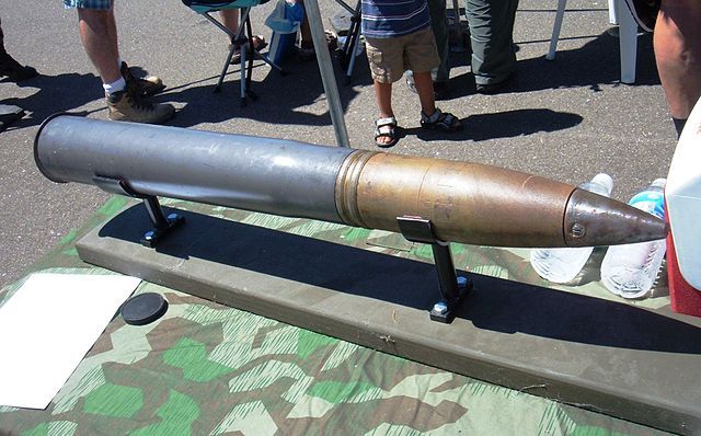 a large metal object sitting on top of a table next to other people standing around