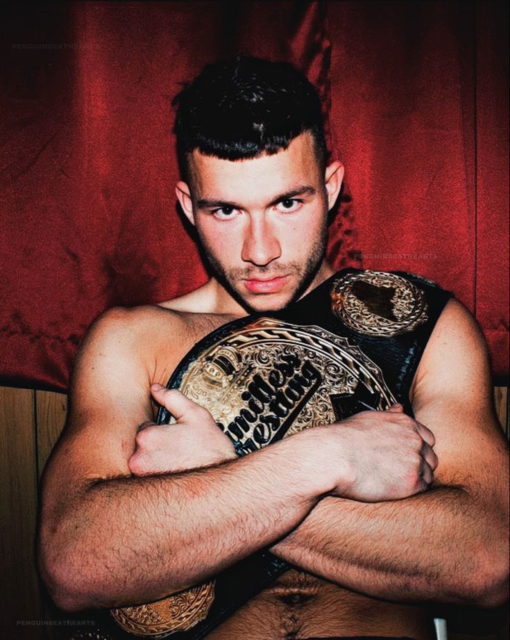 a man with his arms crossed holding a wrestling belt