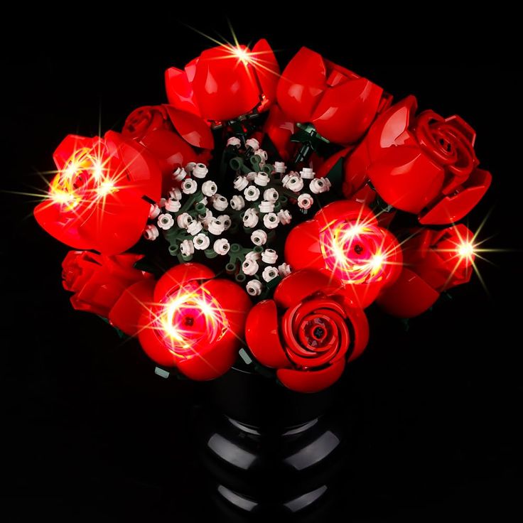 a bouquet of red roses with lights in the middle on a black background, close up