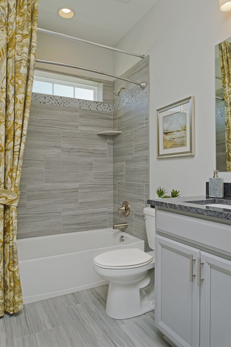 a white toilet sitting in a bathroom next to a bath tub under a window with yellow drapes