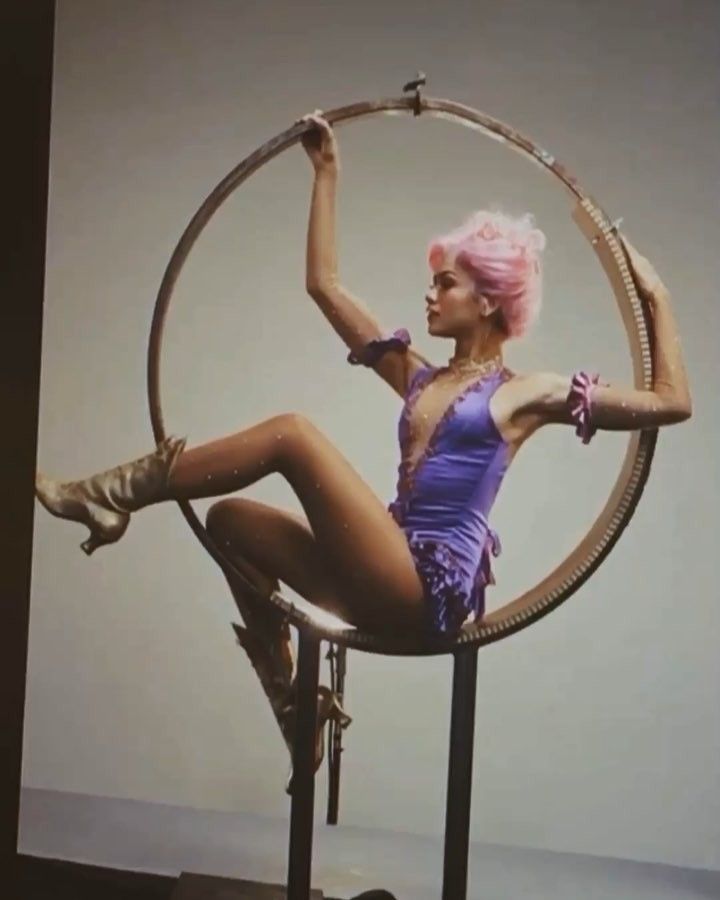 a woman with pink hair is sitting in a hoop