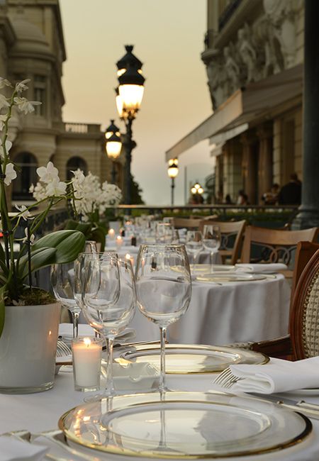 the table is set with wine glasses, plates and flowers in vases on it