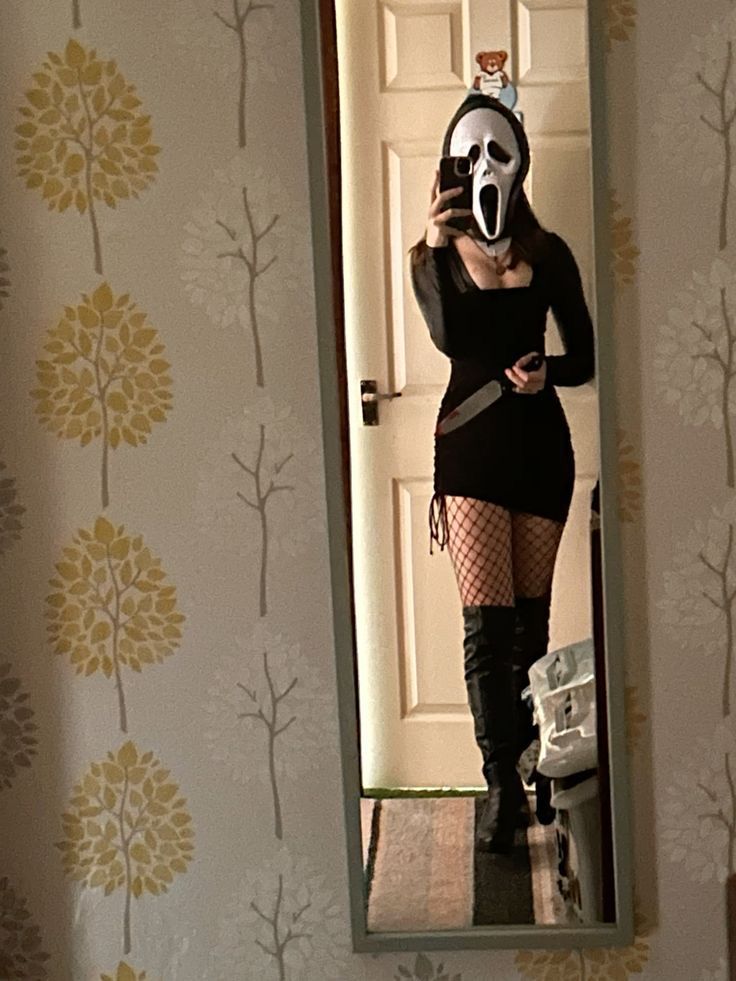 a woman wearing a mask is taking a selfie in front of a mirror with her cell phone