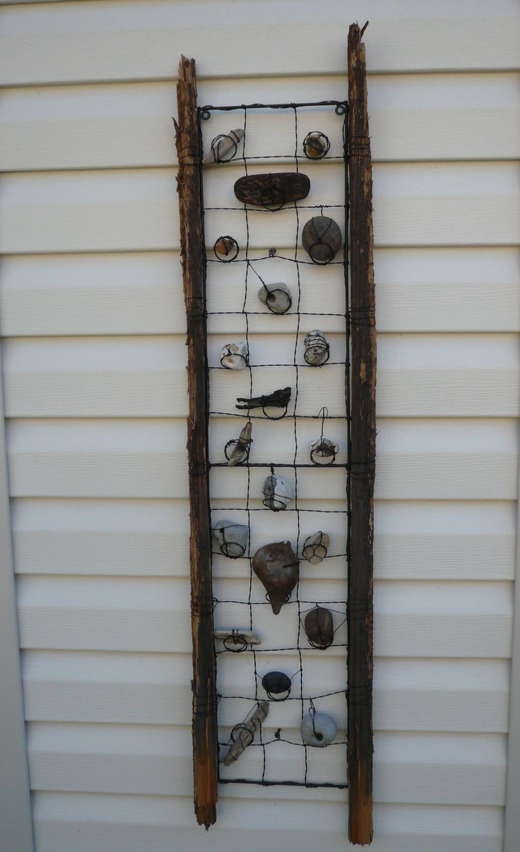 an old ladder with rocks on it hanging from the side of a house