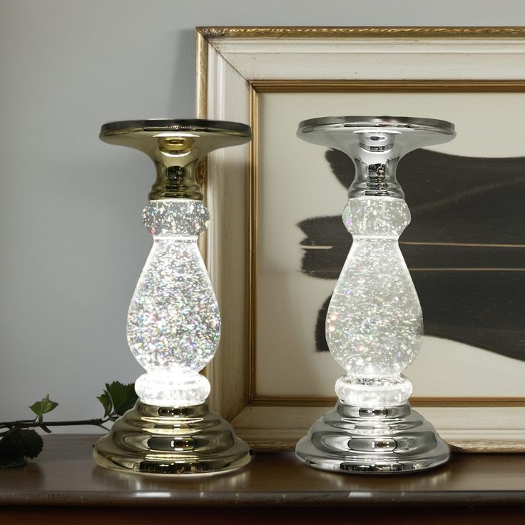 two glass candlesticks sitting on top of a table next to a framed photograph