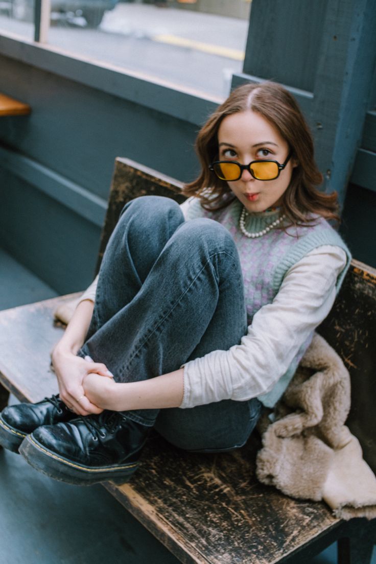 a woman sitting on top of a wooden bench