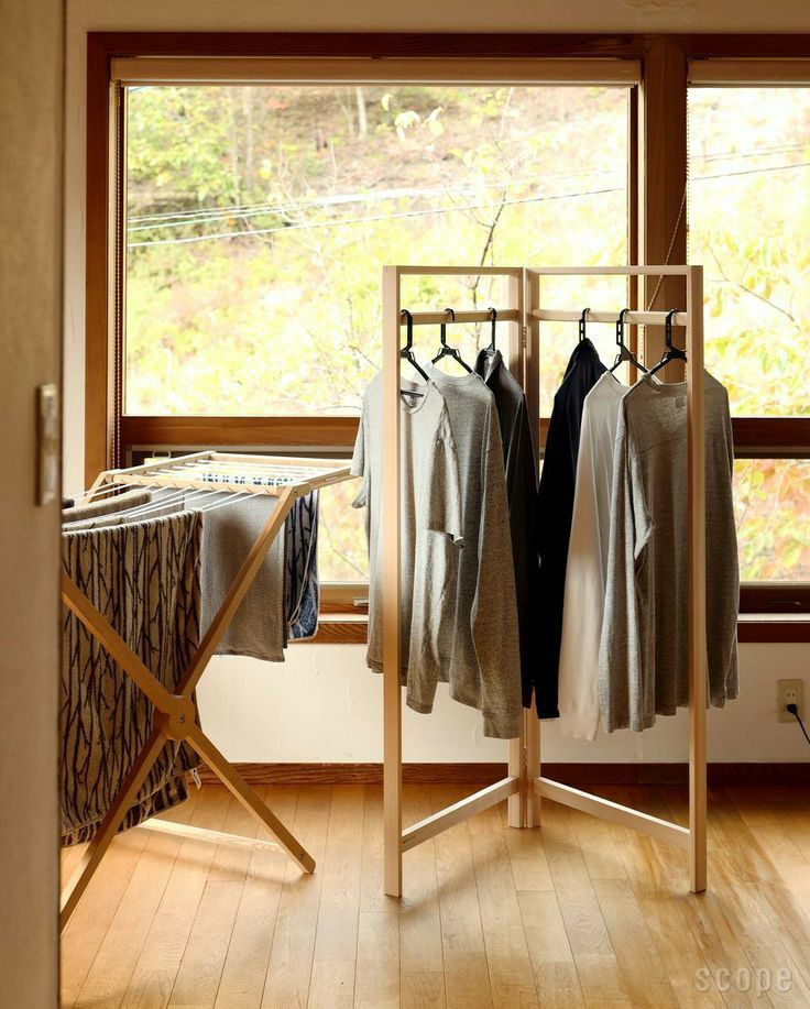 an ironing board with clothes hanging on it in front of a window