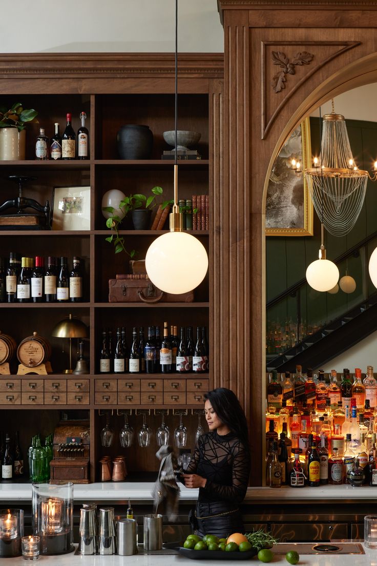 a woman standing behind a bar with lots of bottles