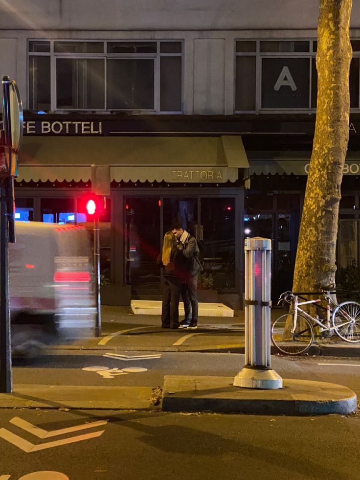 two people standing on the sidewalk at night