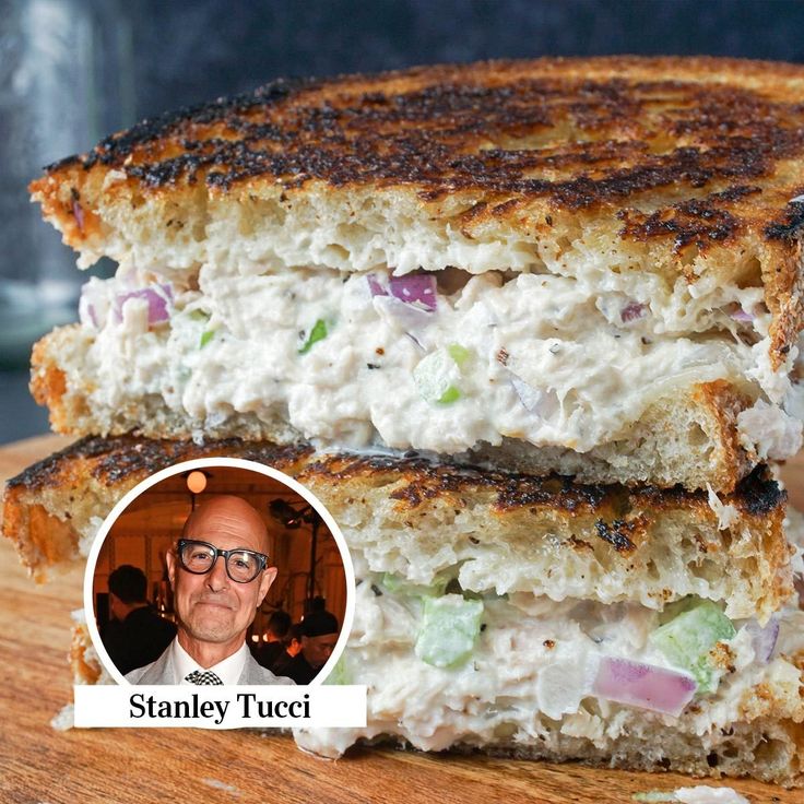 a grilled chicken salad sandwich cut in half on a cutting board with a man's face next to it