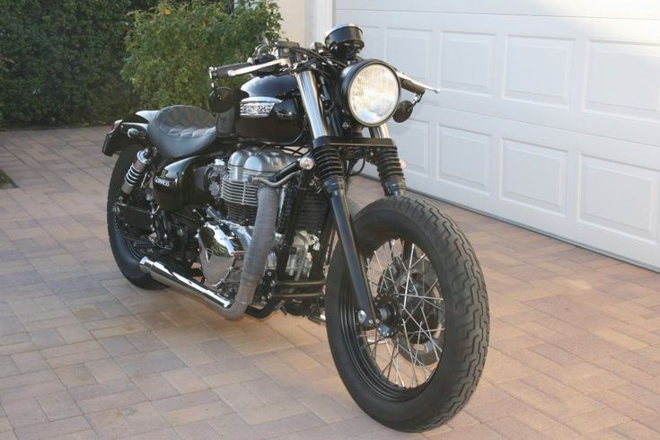 a black motorcycle parked in front of a garage with a white door on the side