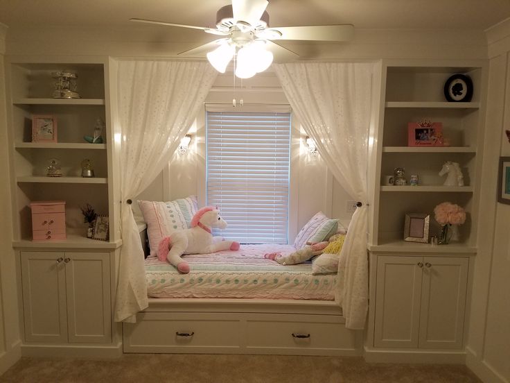 a bedroom with built - in bookshelves and a bed that has a stuffed animal on it