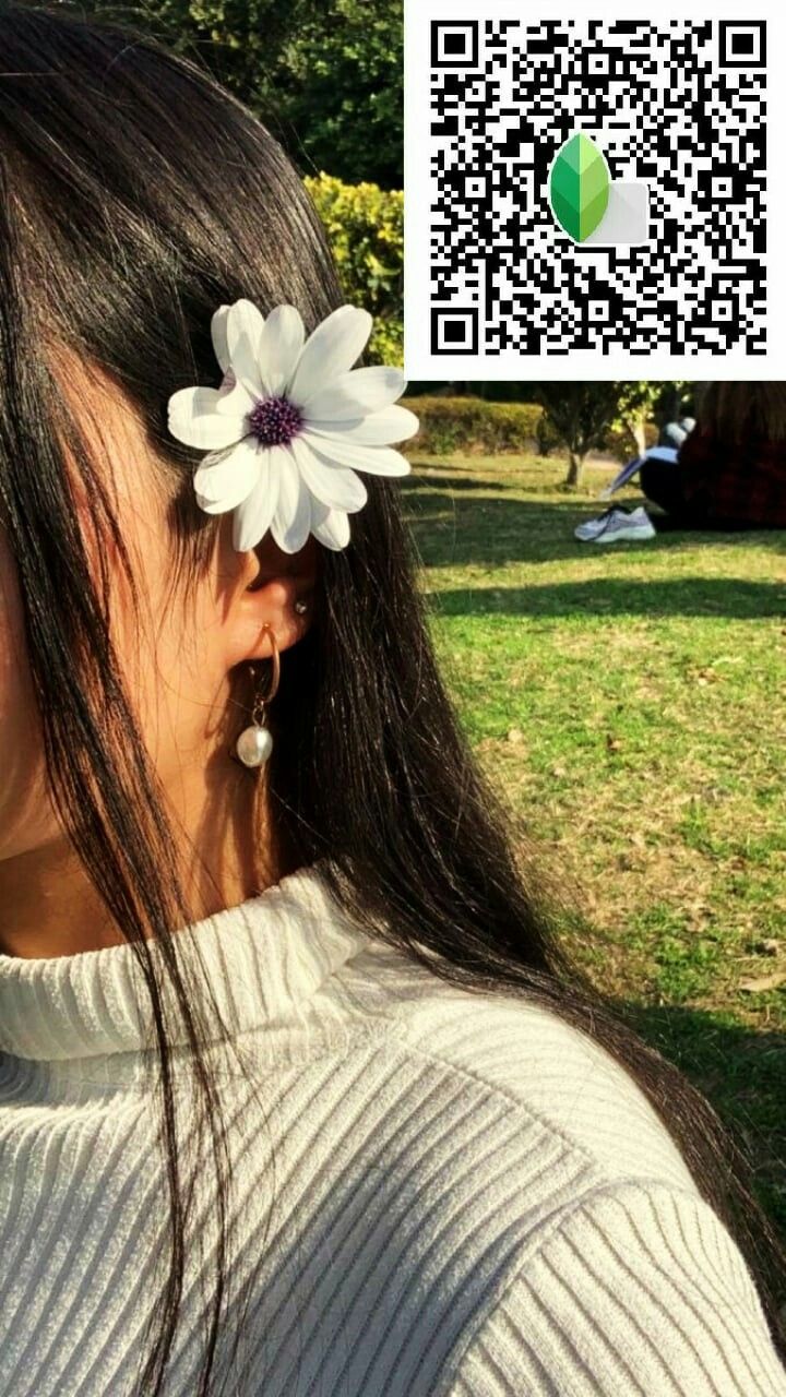 a woman with a flower in her hair and a qr code behind her ear