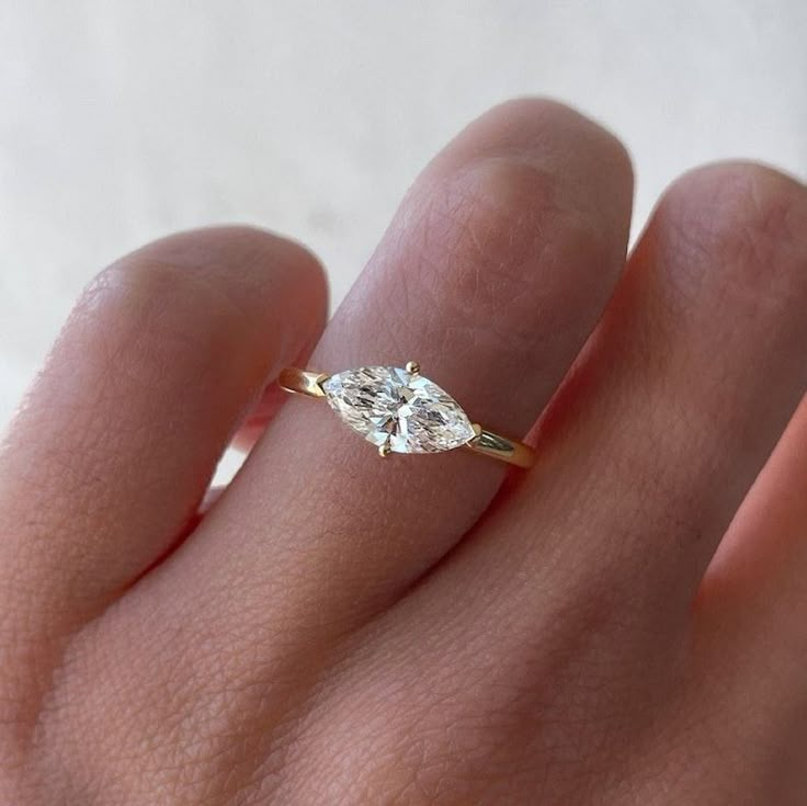 a woman's hand with a diamond ring on top of her finger, showing the center stone