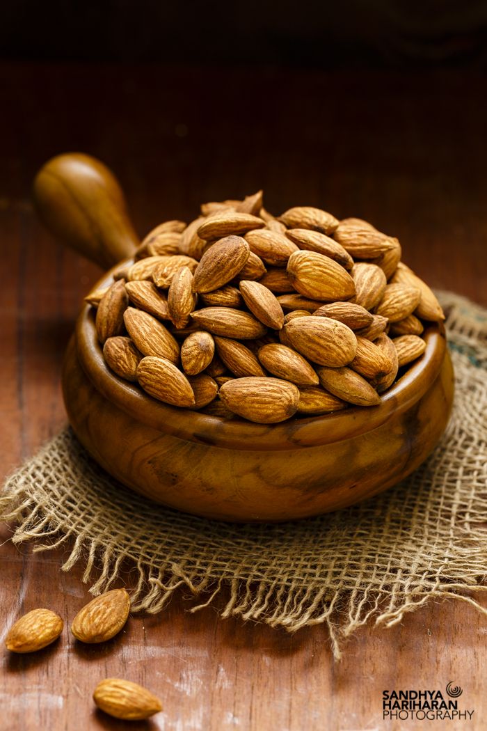 a wooden bowl filled with almonds on top of a table