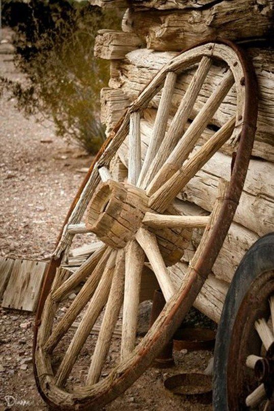 an old wooden wagon sitting on the side of a road