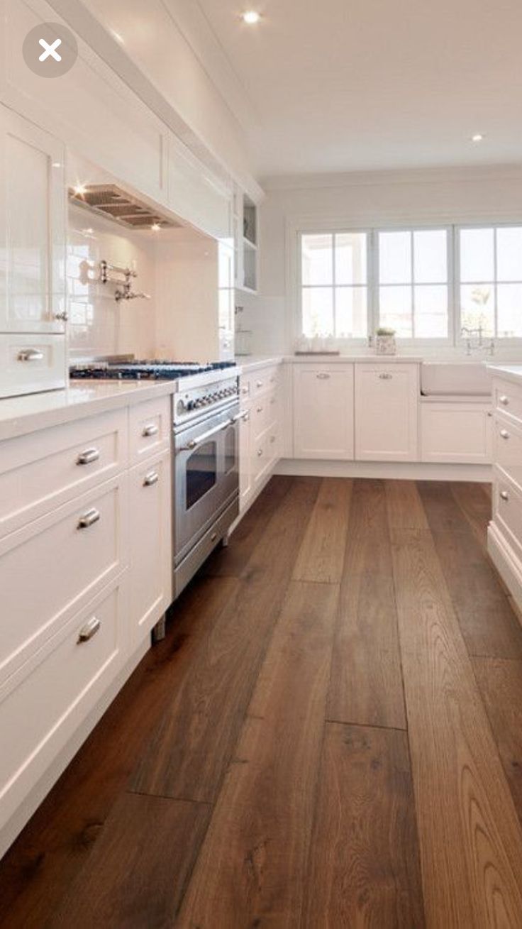 a kitchen with white cabinets and wood floors