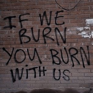 graffiti written on the side of a brick wall reads, if we burn you burn with us