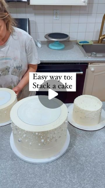 a woman is decorating two cakes with white frosting