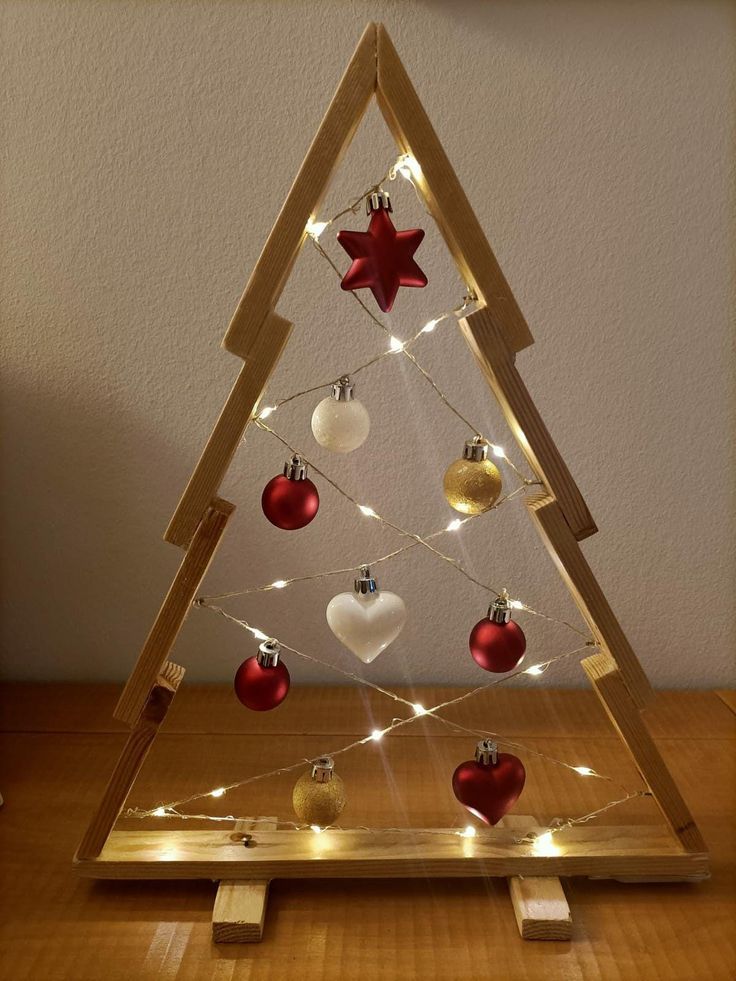 a small wooden christmas tree with lights on it's sides and ornaments hanging from the top