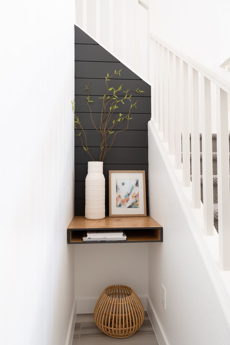 there is a vase with flowers on the shelf next to the stairs in this house