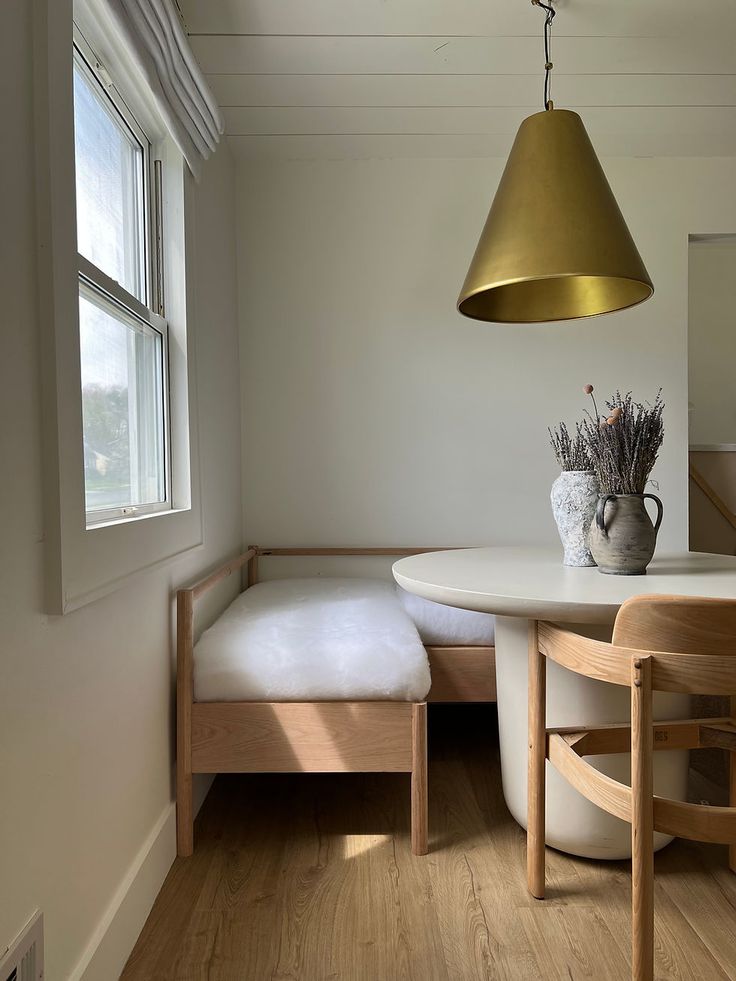 a table with a bench underneath it and a lamp hanging from the ceiling over it