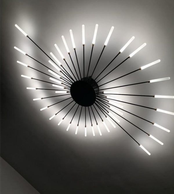 a circular light fixture with white lights on the ceiling in a dark room, against a gray wall